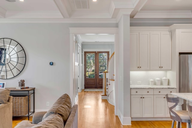 interior space with beam ceiling, stairway, ornamental molding, light wood-type flooring, and coffered ceiling