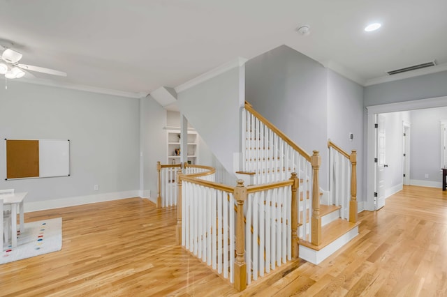 stairs featuring baseboards, crown molding, visible vents, and wood finished floors