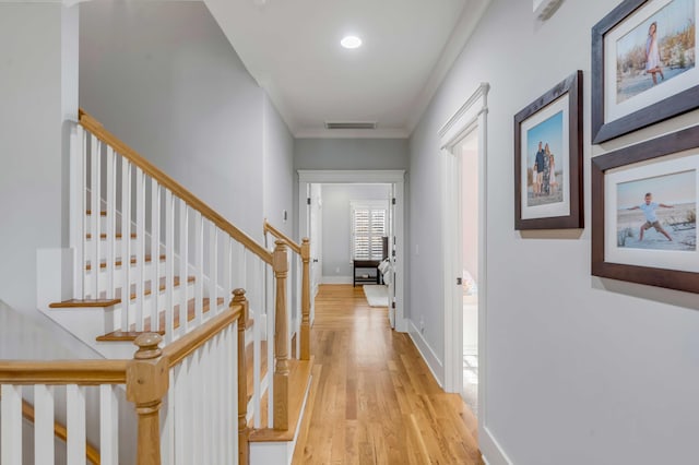 corridor featuring visible vents, baseboards, light wood-style floors, stairway, and crown molding