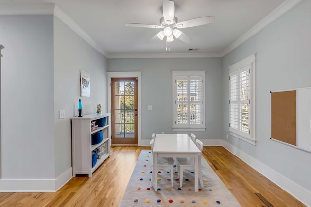 interior space featuring light wood finished floors, baseboards, visible vents, ceiling fan, and ornamental molding