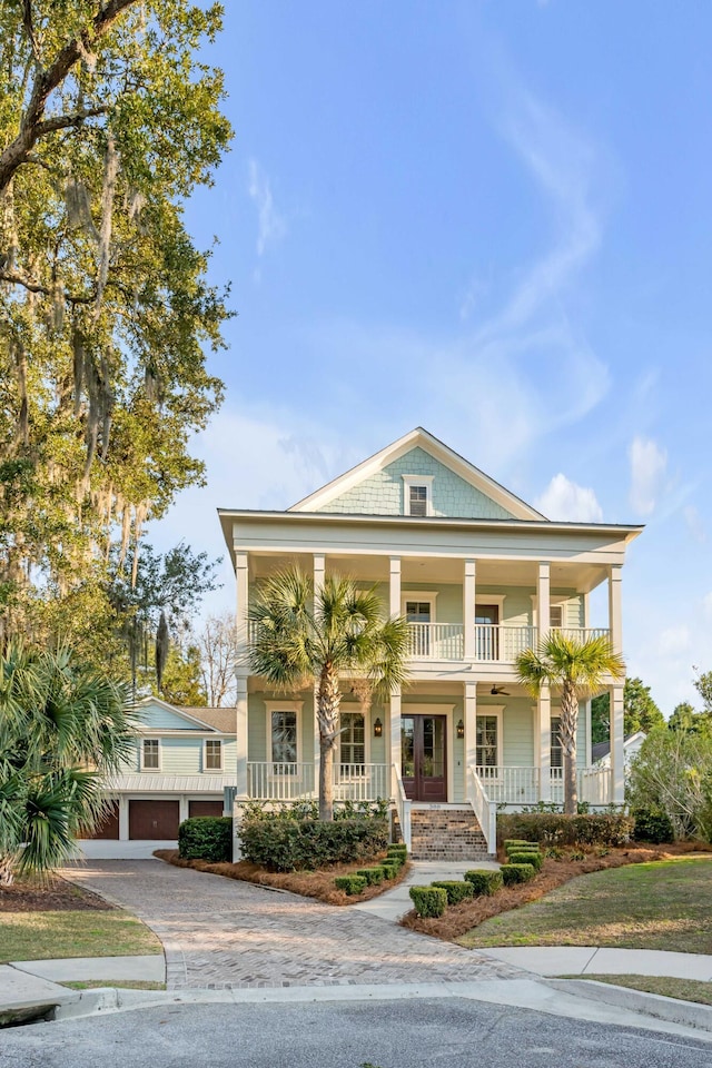 view of front of property with a balcony, a porch, decorative driveway, and french doors