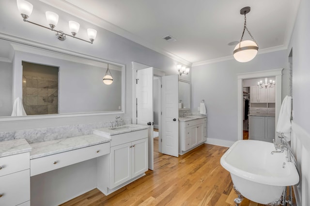 full bathroom featuring visible vents, ornamental molding, wood finished floors, a freestanding bath, and vanity