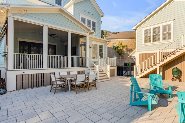 view of patio featuring a sunroom, outdoor dining area, and stairs