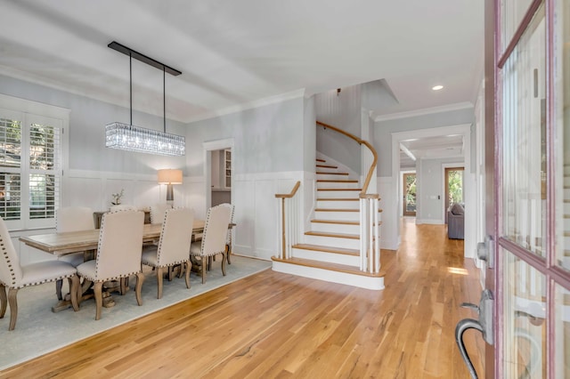 dining space with a wainscoted wall, stairway, wood finished floors, and crown molding