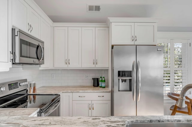 kitchen with stainless steel appliances, a sink, visible vents, and white cabinetry