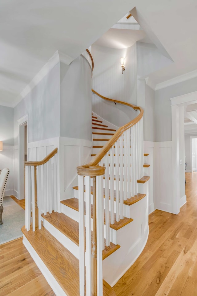 staircase featuring ornamental molding, a wainscoted wall, and wood finished floors