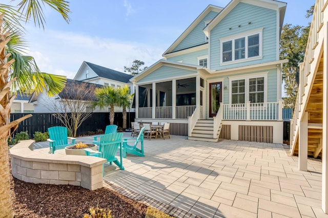 back of house featuring a sunroom, an outdoor fire pit, a patio area, and stairway