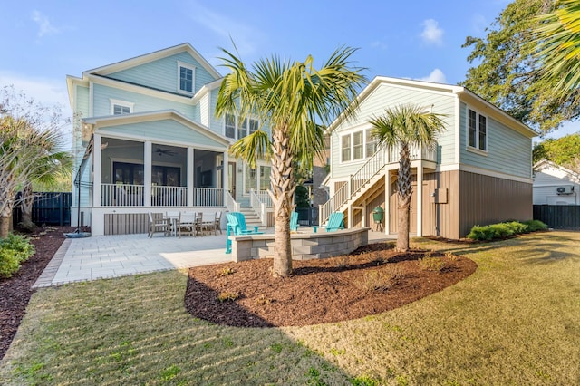 view of front of house featuring stairway, a sunroom, a patio area, fence, and a front lawn