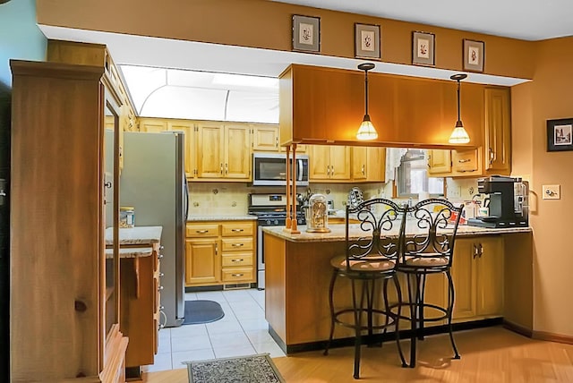 kitchen featuring decorative light fixtures, a breakfast bar area, kitchen peninsula, stainless steel appliances, and light stone countertops