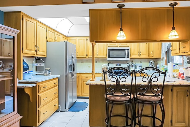 kitchen featuring light stone counters, appliances with stainless steel finishes, hanging light fixtures, and light tile patterned floors