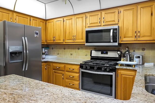 kitchen with light stone counters, tasteful backsplash, and appliances with stainless steel finishes