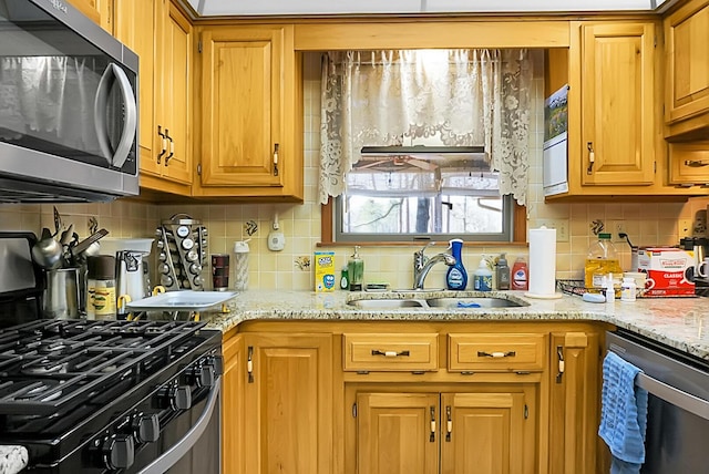 kitchen with stainless steel appliances, sink, light stone counters, and decorative backsplash