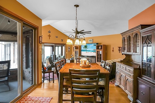 dining space with lofted ceiling, an inviting chandelier, and light hardwood / wood-style flooring