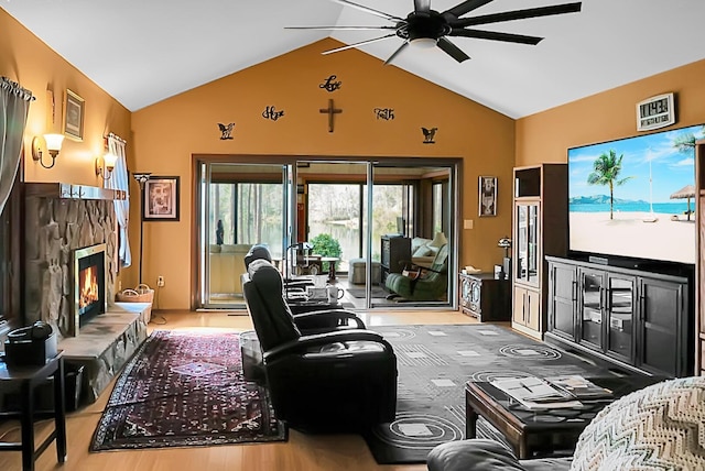 living room with hardwood / wood-style flooring, a stone fireplace, lofted ceiling, and ceiling fan