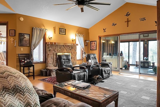 living room with vaulted ceiling, a stone fireplace, hardwood / wood-style floors, and ceiling fan