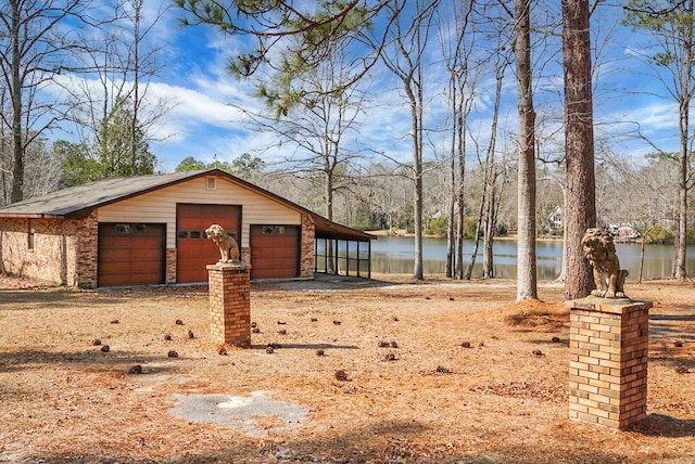 view of yard with an outbuilding, a garage, and a water view