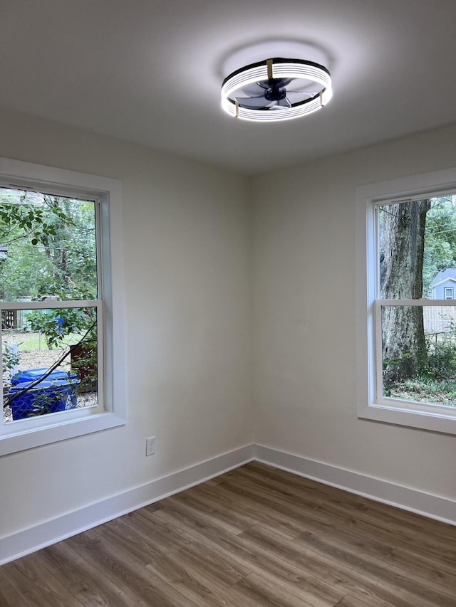 spare room featuring baseboards and dark wood-style floors