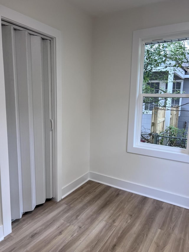 unfurnished bedroom featuring a closet, baseboards, and wood finished floors