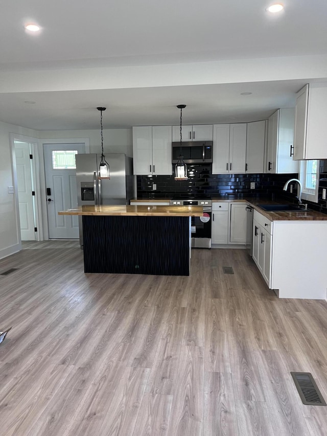 kitchen with visible vents, a sink, appliances with stainless steel finishes, tasteful backsplash, and a center island