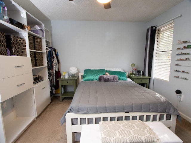 bedroom with a textured ceiling, light carpet, and ceiling fan