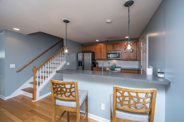 kitchen featuring pendant lighting, appliances with stainless steel finishes, kitchen peninsula, and decorative backsplash