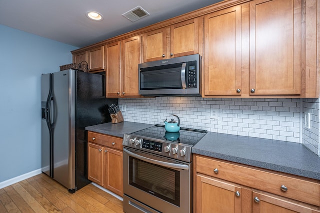 kitchen with backsplash, stainless steel appliances, and light wood-type flooring