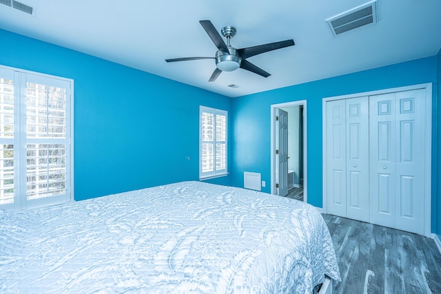 bedroom featuring connected bathroom, dark wood-type flooring, a closet, and ceiling fan