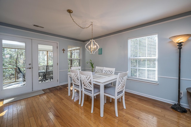 dining space with french doors, an inviting chandelier, light hardwood / wood-style flooring, and a wealth of natural light