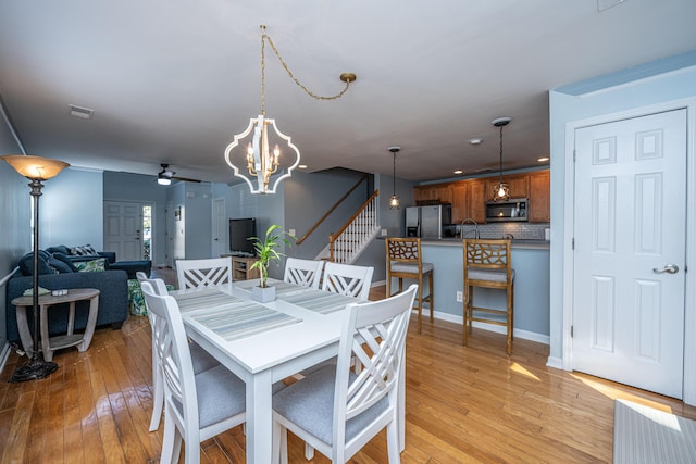 dining space featuring ceiling fan with notable chandelier and light wood-type flooring