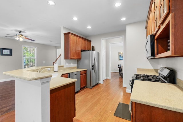 kitchen with sink, ceiling fan, appliances with stainless steel finishes, light hardwood / wood-style floors, and kitchen peninsula