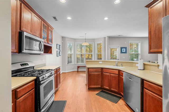 kitchen with decorative light fixtures, light wood-type flooring, sink, and appliances with stainless steel finishes