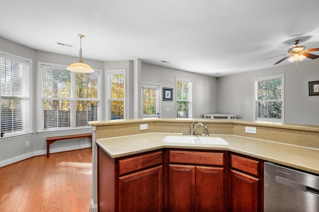 kitchen featuring sink, stainless steel dishwasher, ceiling fan, decorative light fixtures, and light hardwood / wood-style floors