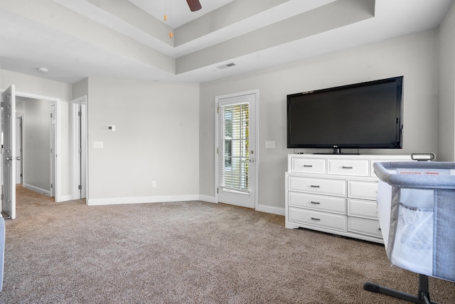 interior space with a tray ceiling, ceiling fan, and light colored carpet