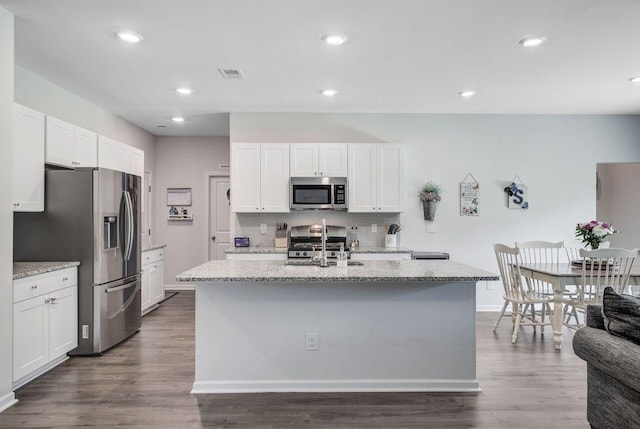 493 Spanish Wells Rd, Summerville, SC 29486 - kitchen with stainless steel appliances, an island with sink, dark wood-style floors, light stone countertops, and recessed lighting