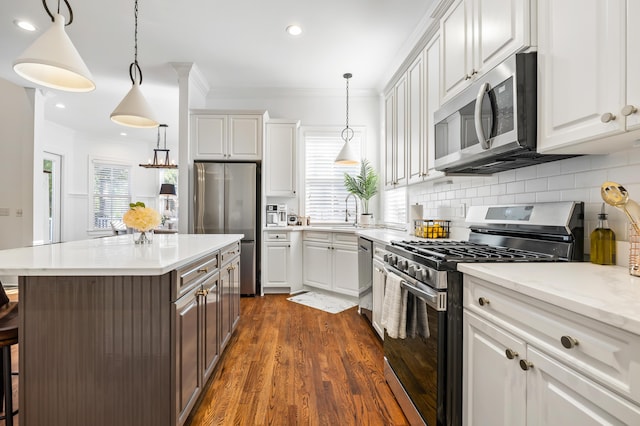 4009 E Amy Ln, Johns Island, SC 29455 - kitchen with stainless steel appliances, a breakfast bar area, crown molding, white cabinets, and backsplash