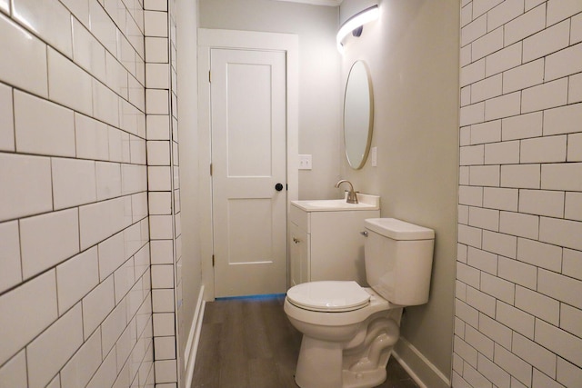 bathroom with wood finished floors, vanity, toilet, and baseboards