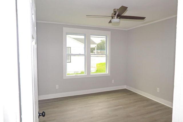 spare room featuring baseboards, wood finished floors, a ceiling fan, and crown molding