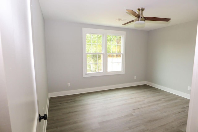 unfurnished room featuring ceiling fan, wood finished floors, visible vents, and baseboards