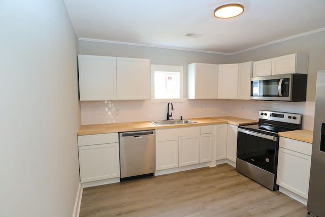 kitchen featuring light wood finished floors, visible vents, appliances with stainless steel finishes, a sink, and backsplash