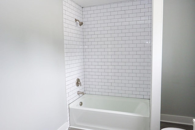 bathroom with shower / bath combination, toilet, and baseboards