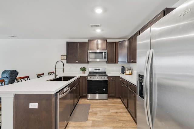 kitchen with visible vents, appliances with stainless steel finishes, light countertops, dark brown cabinets, and a sink