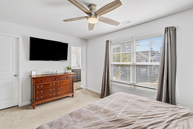 bedroom with light carpet, baseboards, visible vents, ensuite bath, and ceiling fan