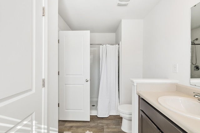 bathroom with toilet, wood finished floors, vanity, and a shower with curtain