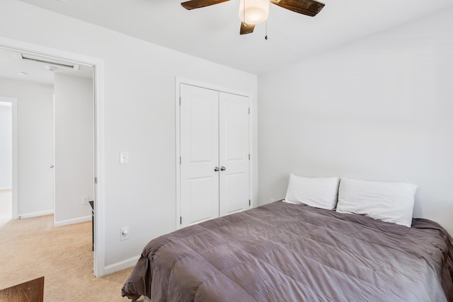 bedroom featuring light carpet, ceiling fan, baseboards, and a closet