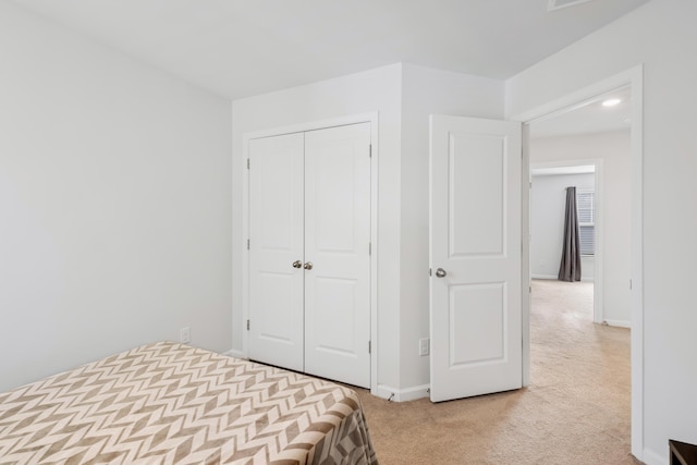 unfurnished bedroom featuring a closet, light carpet, and baseboards