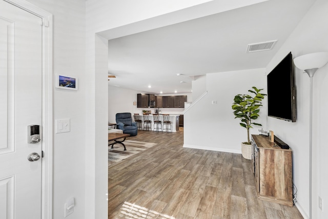 foyer with light wood finished floors, baseboards, and visible vents