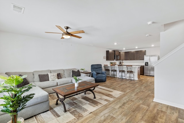 living area featuring visible vents, baseboards, ceiling fan, light wood-style floors, and recessed lighting