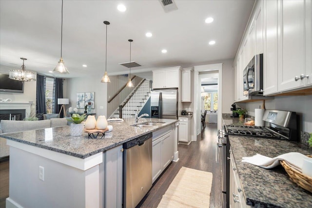 kitchen featuring pendant lighting, white cabinets, stainless steel appliances, and a kitchen island with sink