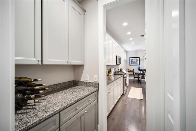 kitchen with dark wood-type flooring, white cabinetry, appliances with stainless steel finishes, and stone counters