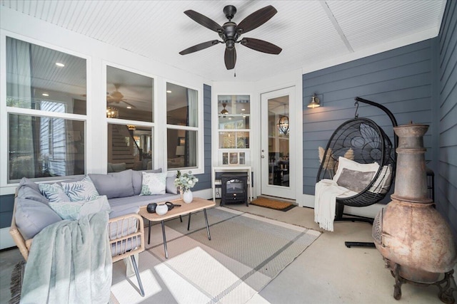 sunroom with a wood stove and ceiling fan